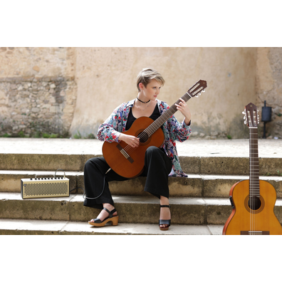 Stephanie Jones seated on stone steps playing CGX122MC and CGX122MS leaning on steps in Spain