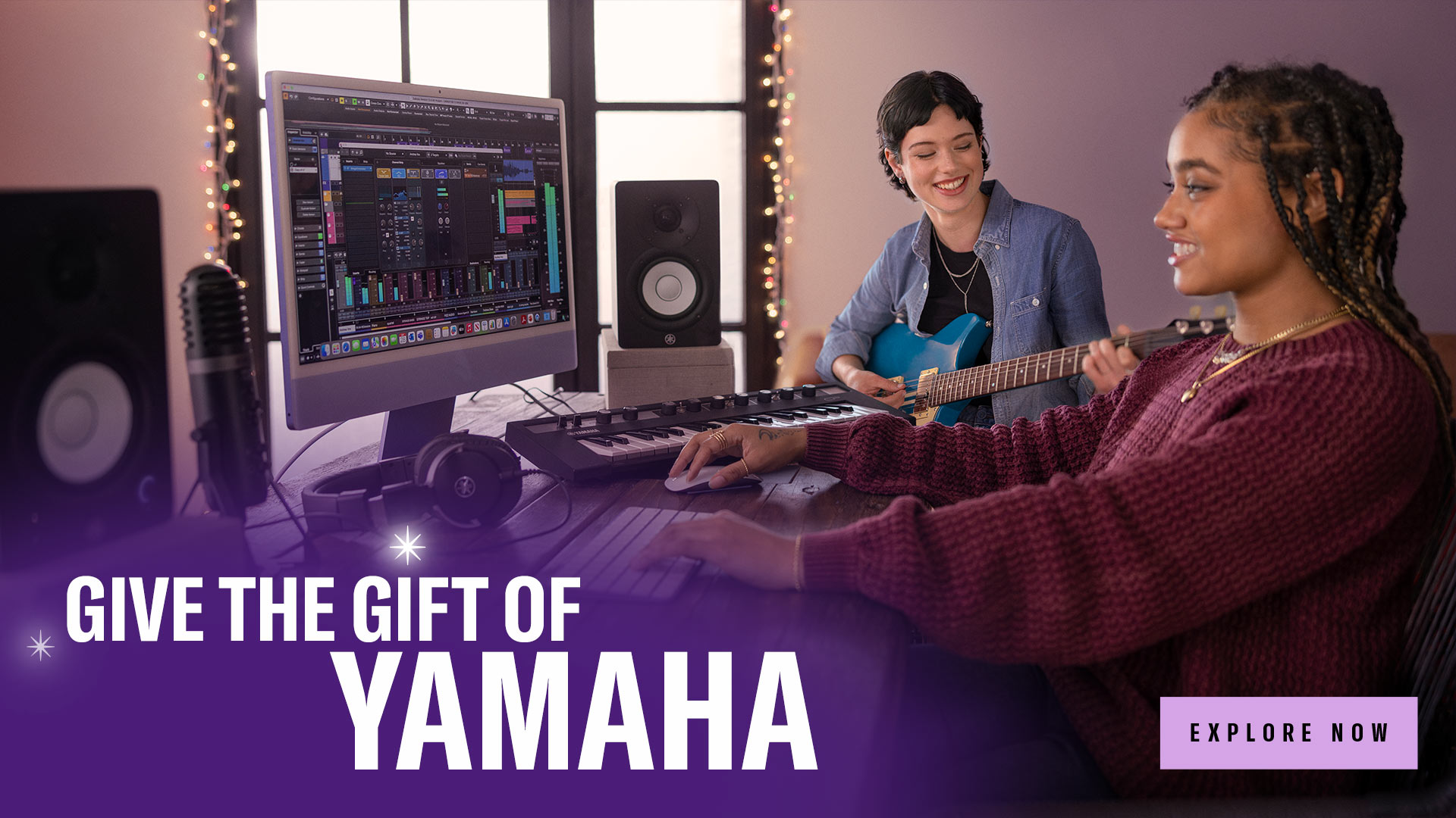 a girl is seen using computer and another female is playing yamaha guitar