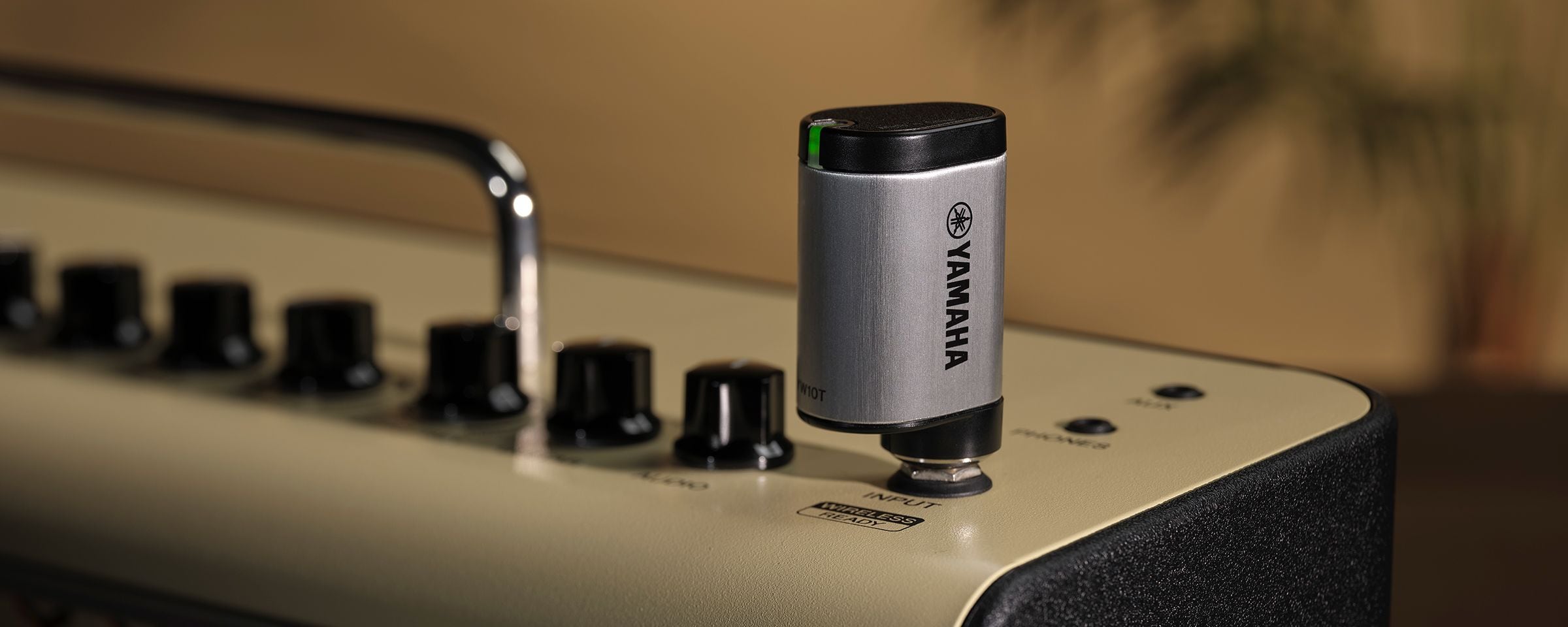 The YW10T is plugged into the THR30II Wireless guitar amp. Focus of the image is the YW10T that shows Yamaha logo with the LED flashing green.