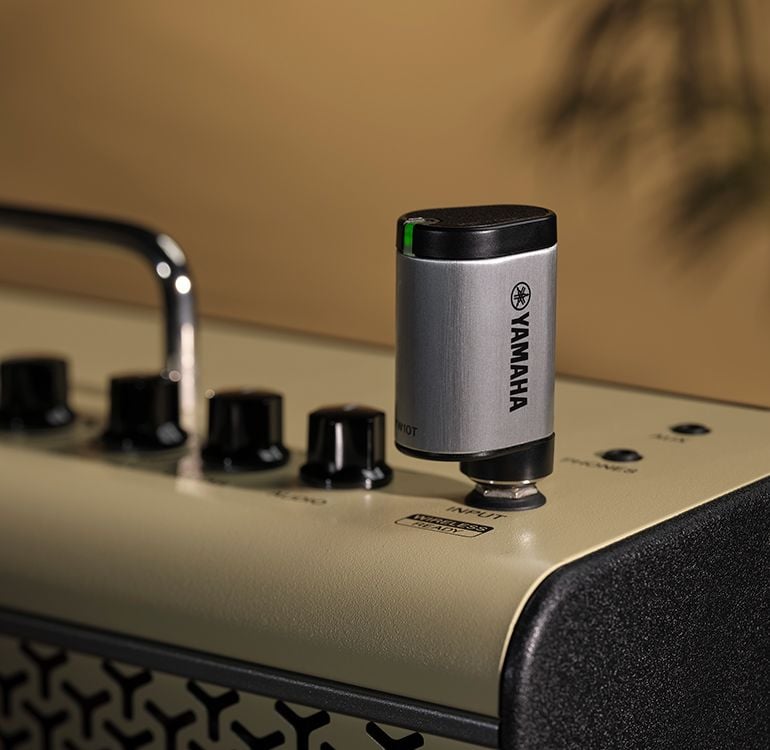 The YW10T is plugged into the THR30II Wireless guitar amp. Focus of the image is the YW10T that shows Yamaha logo with the LED flashing green.