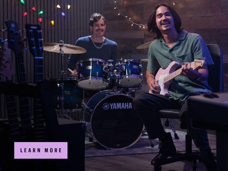 two men performing with Yamaha drums and electric guitar