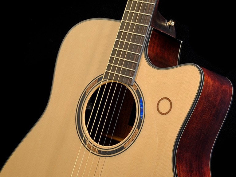 Beauty shot of the TAG3 C in Natural finish showing the detail of the sound hole blue-pattern inlay and looper touch control on the solid spruce top.