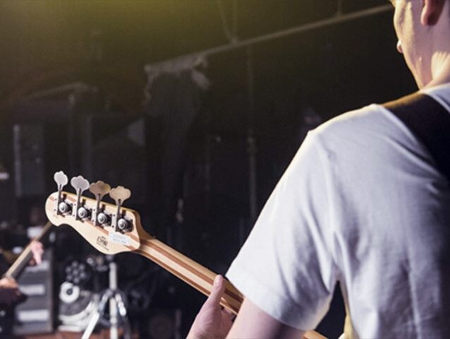 Over the shoulder of bassist playing BB and looking at another musician.